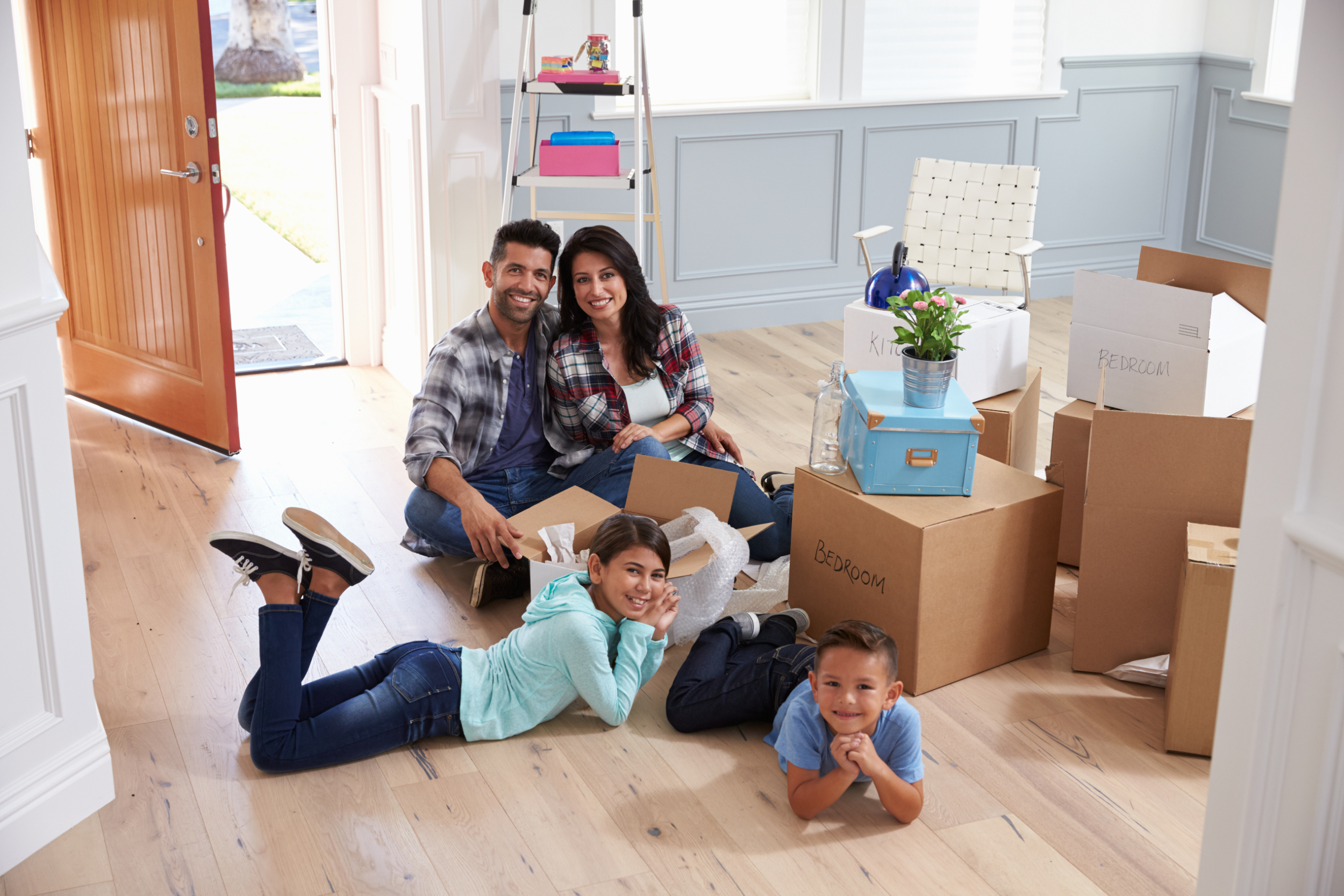 A young family smiling with moving boxes in a new home