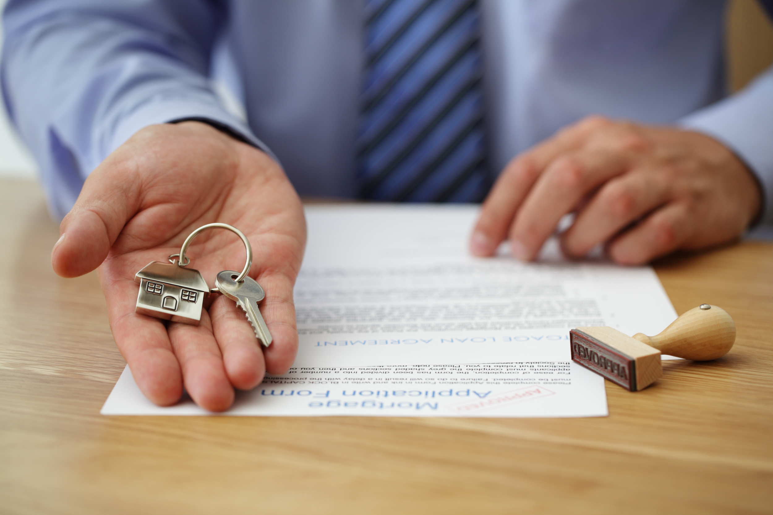 A man holding keys to a new home next to a mortgage contract