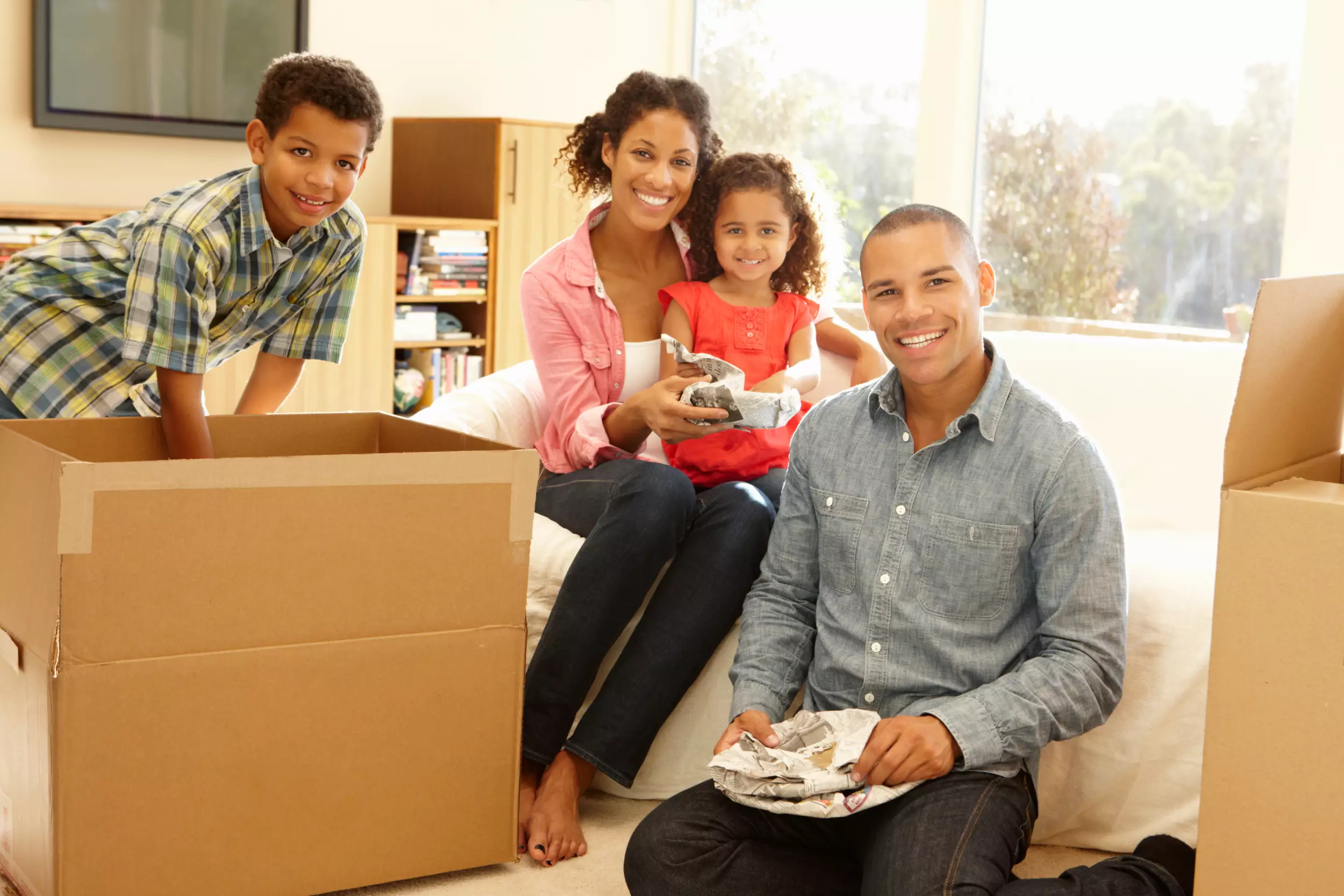 A young family smiling with moving boxes in a new home