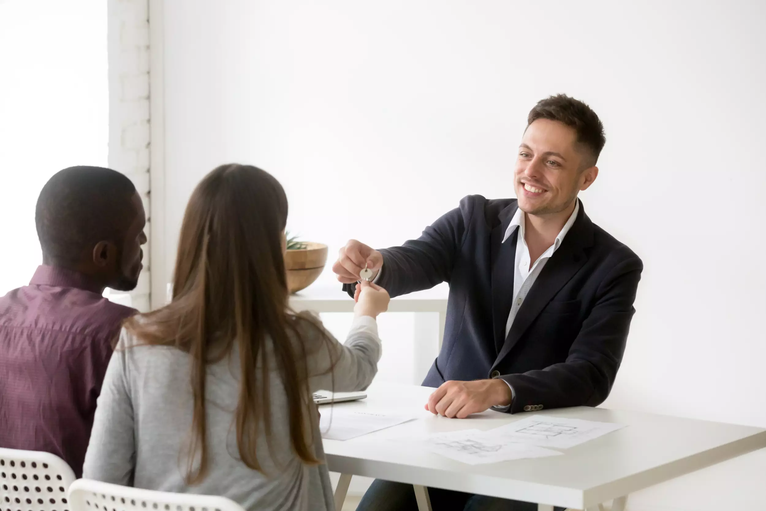 A young title agent hands keys to a new home to a young couple