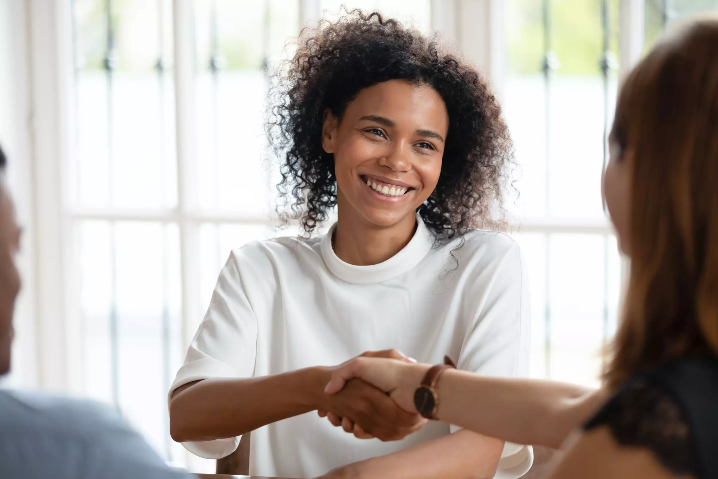 A young woman smiles and shakes hands